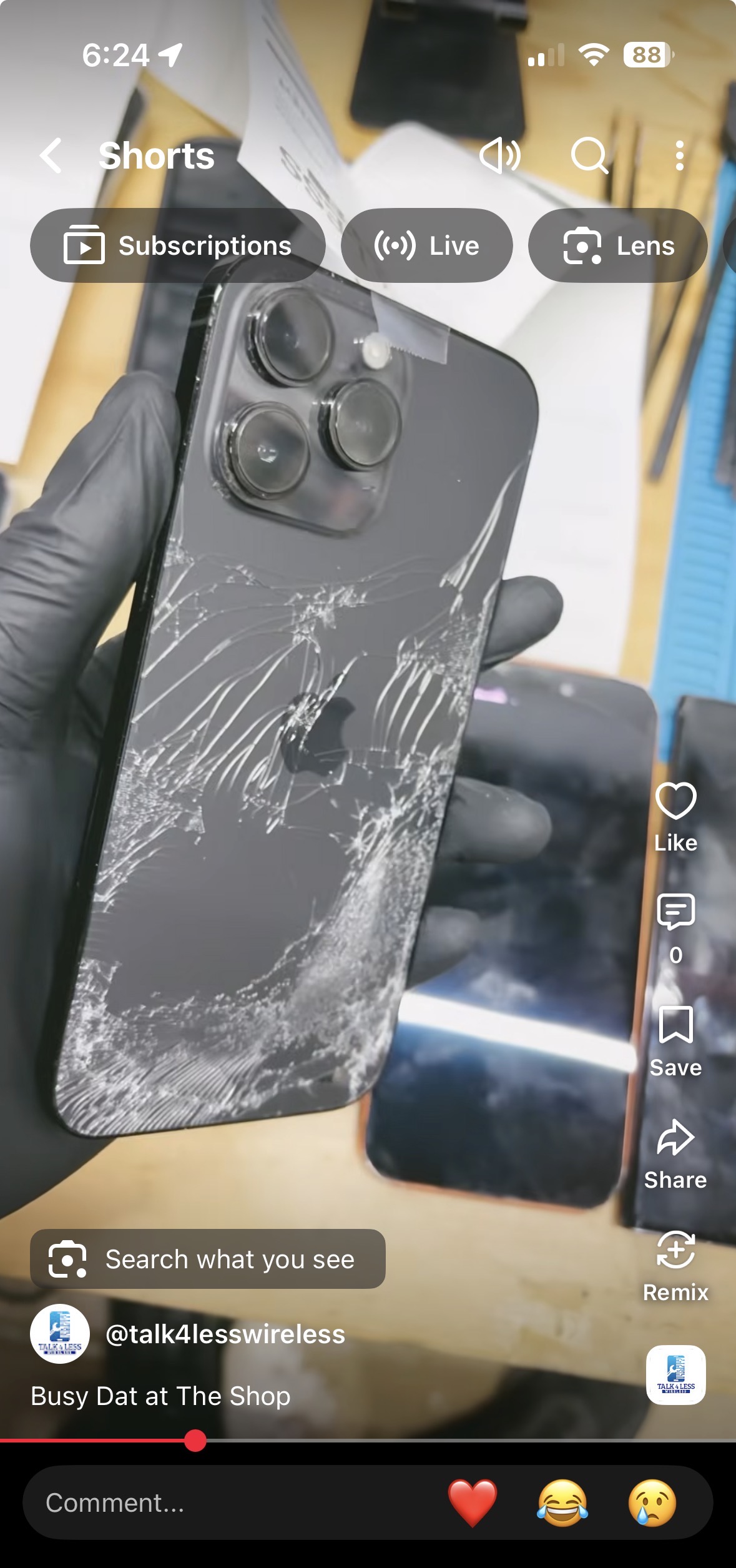 Cracked iPhone back held in black repair gloves at Talk 4 Less Wireless